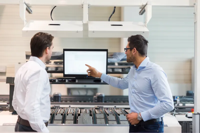 two-businessmen-talking-at-screen-in-modern-factor-2022-12-16-22-37-57-utc